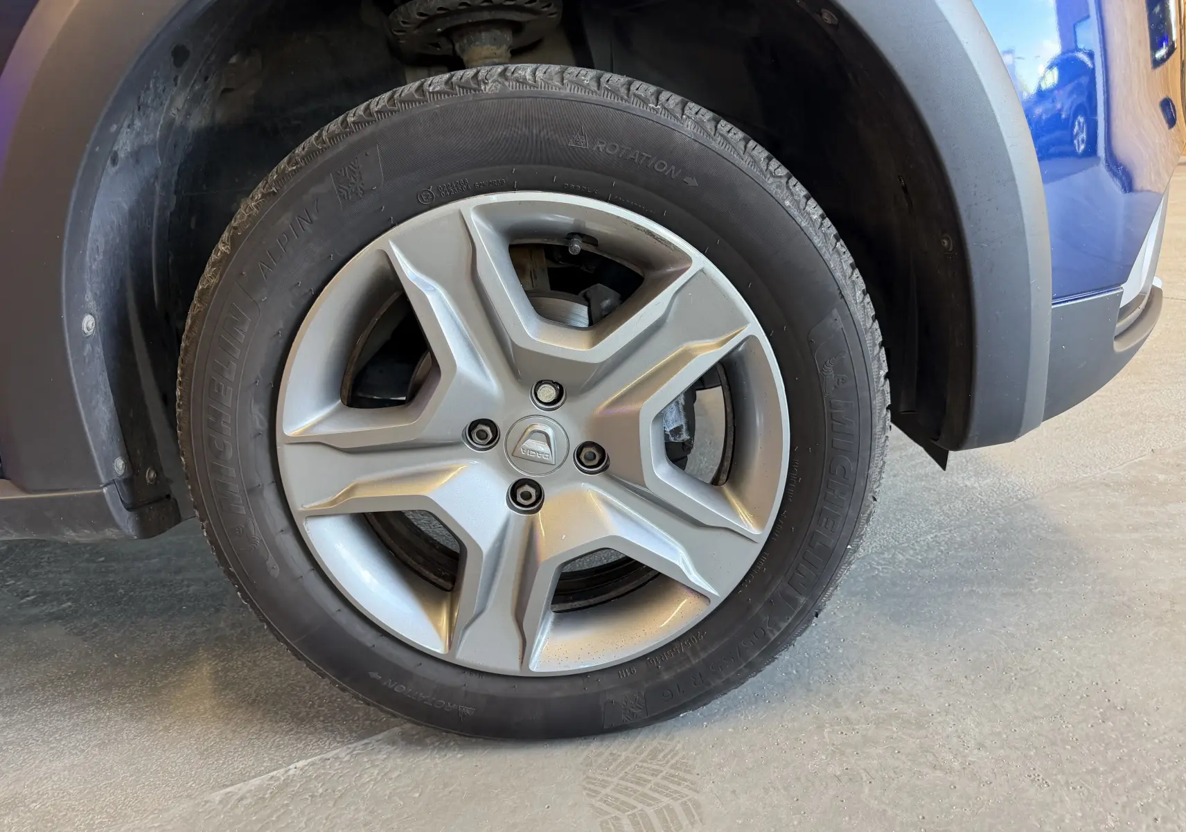Gros plan sur la roue avant droite d’une Dacia Sandero Stepway bleue de 2019 avec jante alliage et pneu Michelin.
