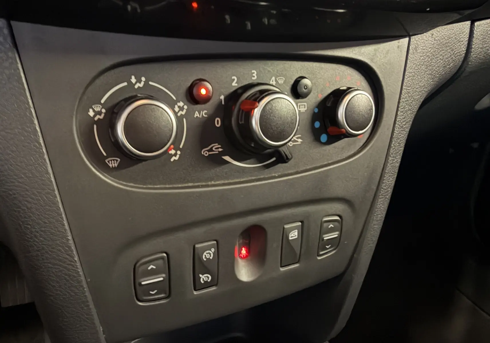 Vue rapprochée des commandes de climatisation et des boutons de réglage du tableau de bord d’une Dacia Sandero Stepway bleu 2019.
