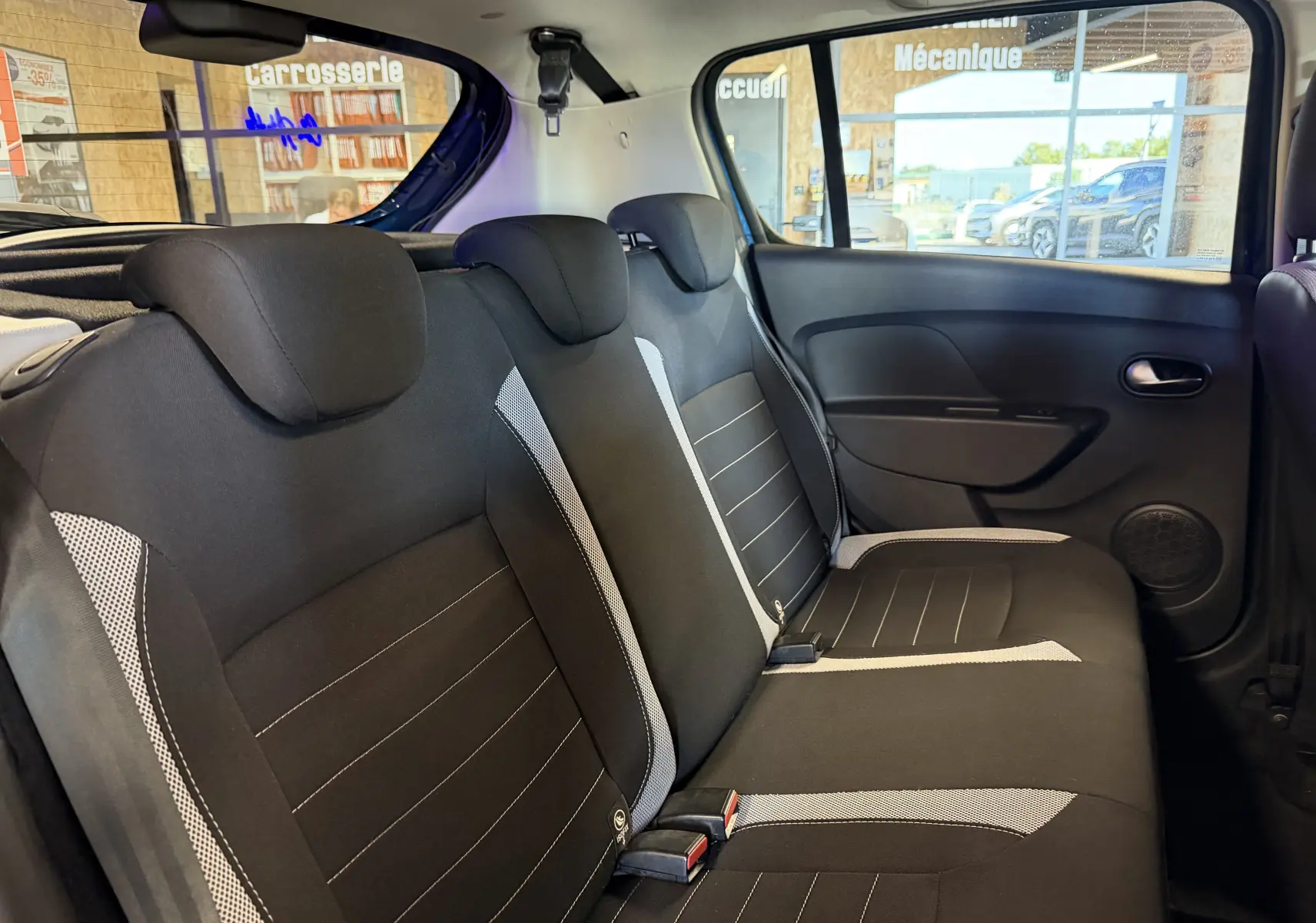 Vue intérieure côté droit des sièges arrière noirs avec inserts gris du Dacia Sandero Stepway 2019, dans un garage.