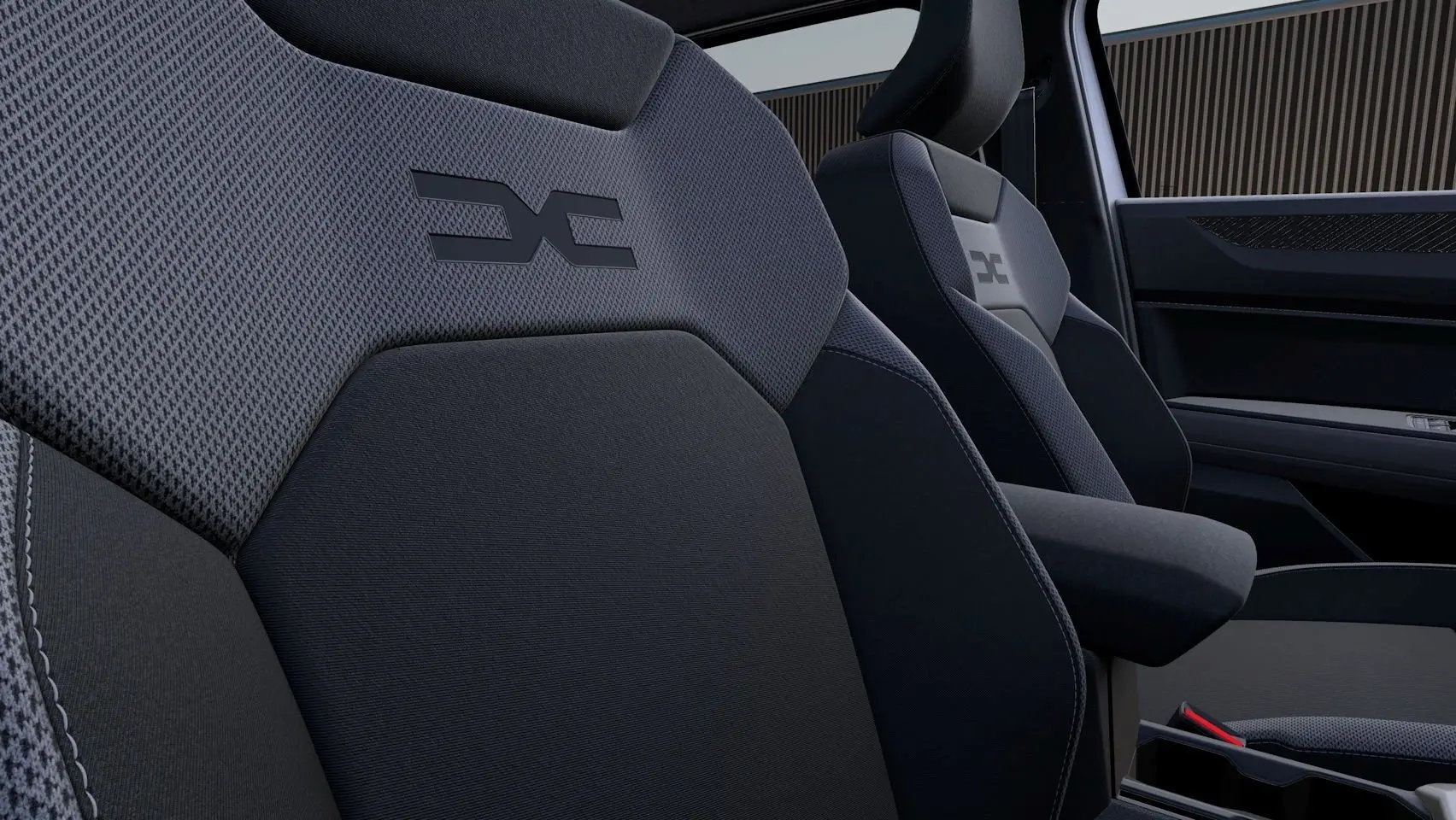 Gros plan sur les sièges avant en tissu gris foncé avec logo Dacia embossé, intérieur moderne et épuré.