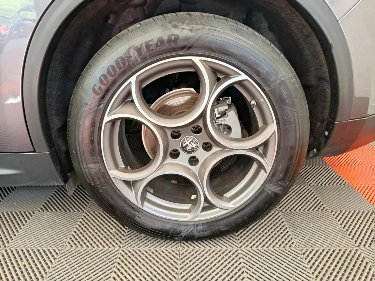 Gros plan sur la roue avant droite gris foncé d’un Alfa Romeo Stelvio 2024 avec jante en alliage à motif circulaire distinctif.