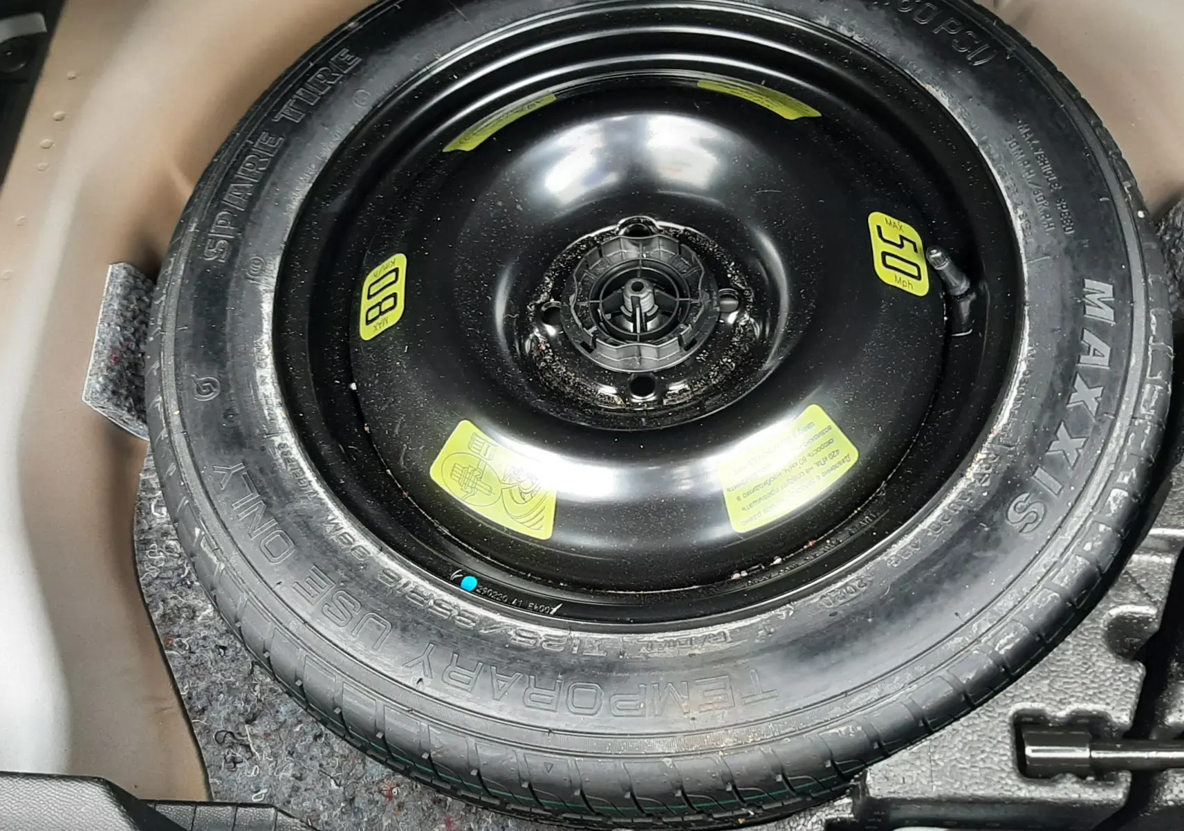 Gros plan sur la roue de secours noire dans le coffre du Peugeot 2008 gris Artense de 2020.