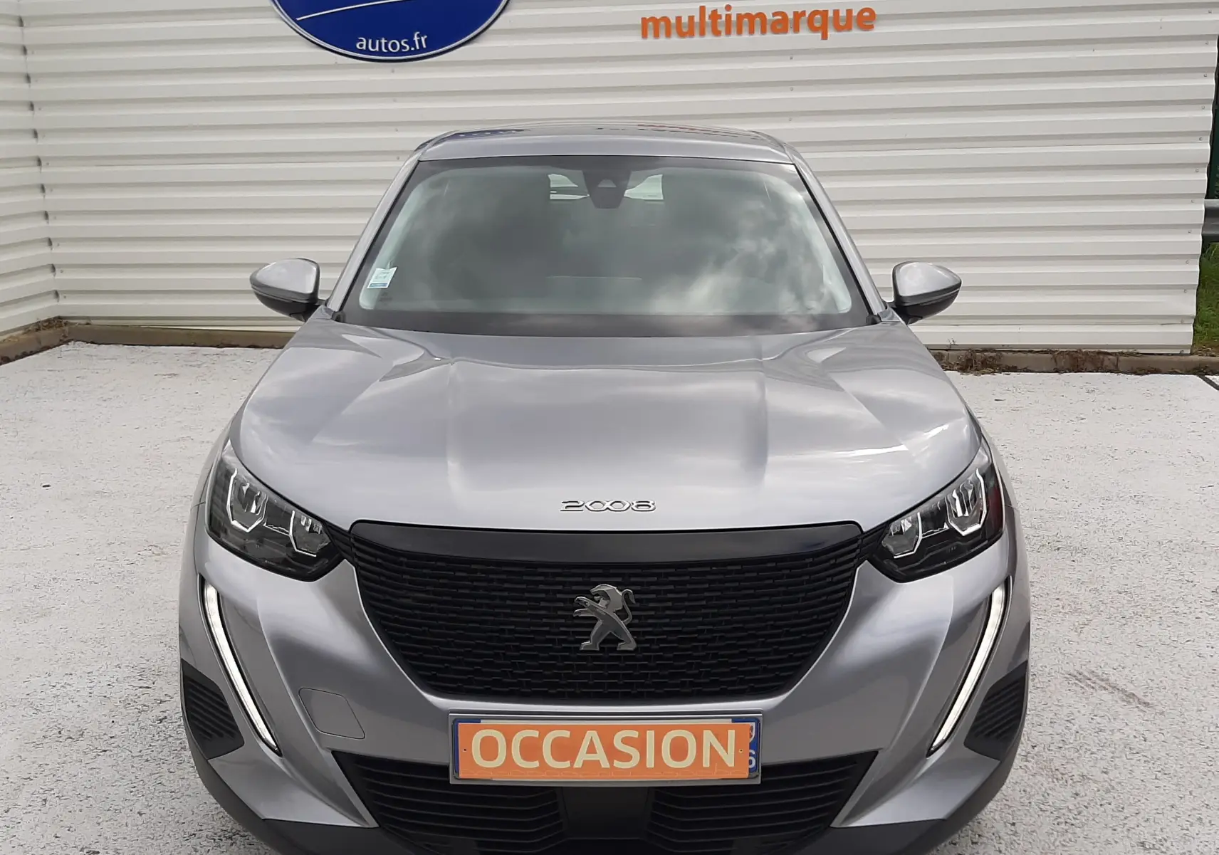 Vue frontale d'un Peugeot 2008 gris Artense 2020 avec calandre noire et feux LED, plaque "OCCASION" visible.