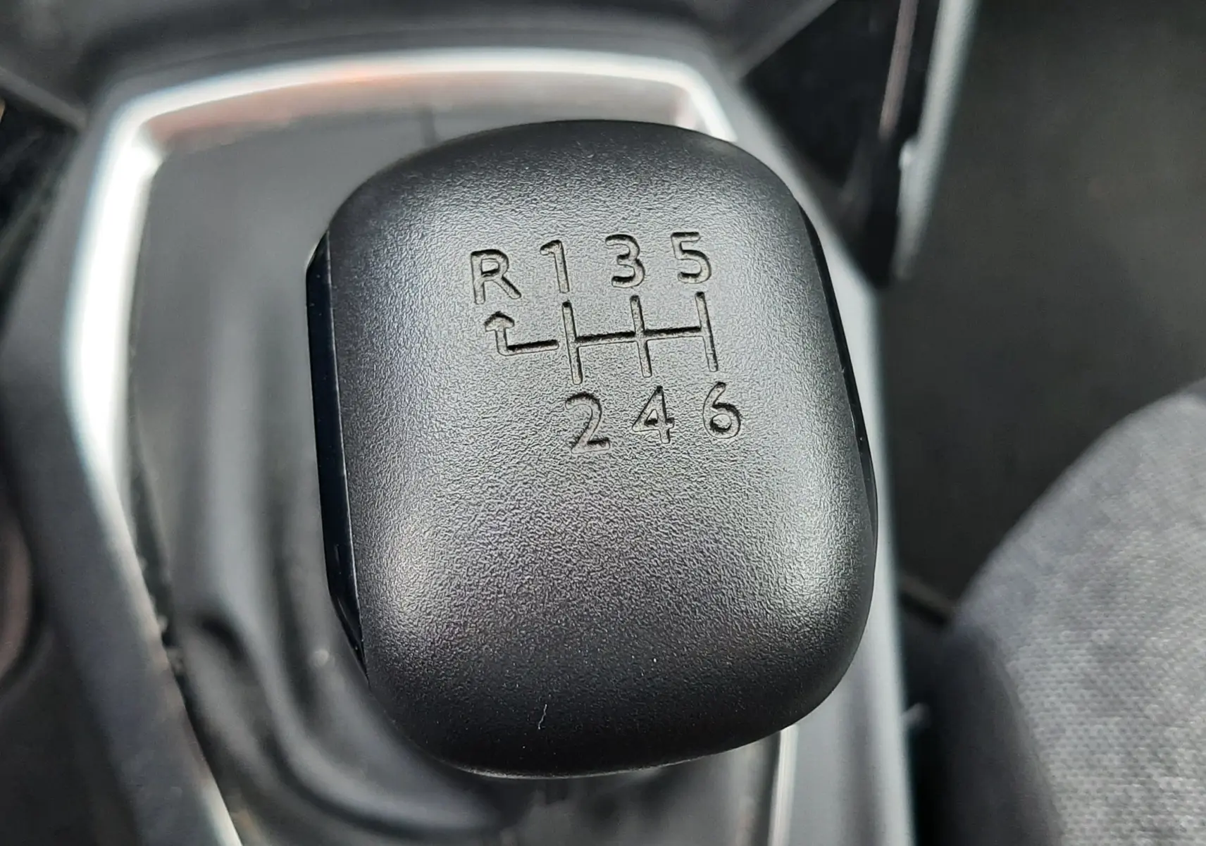 Gros plan sur le levier de vitesses manuel noir du Peugeot 2008 gris Artense, montrant les six rapports et la marche arrière.