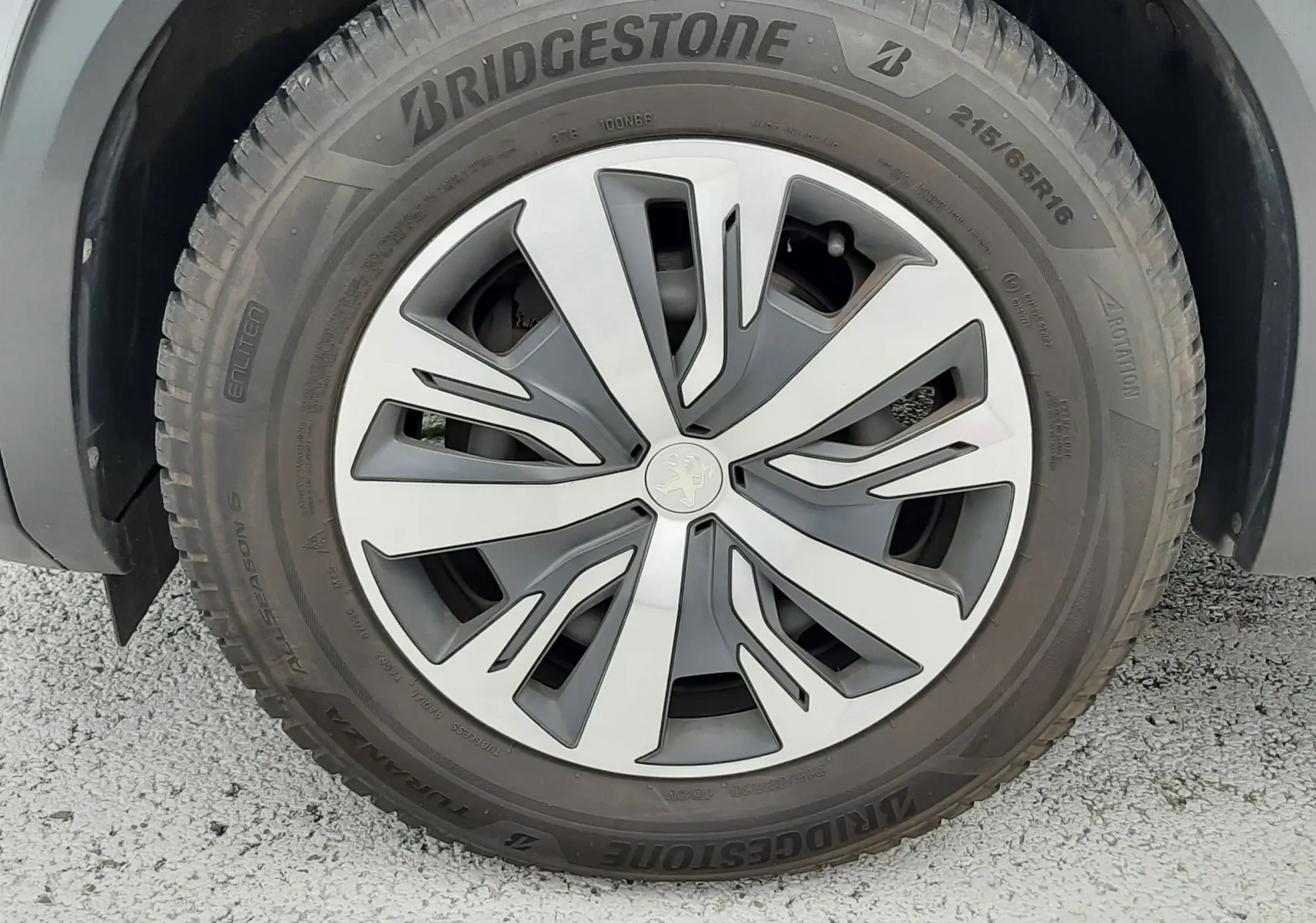 Gros plan sur la roue avant droite d’un Peugeot 2008 gris Artense avec jante alliage au design moderne et pneu Bridgestone.