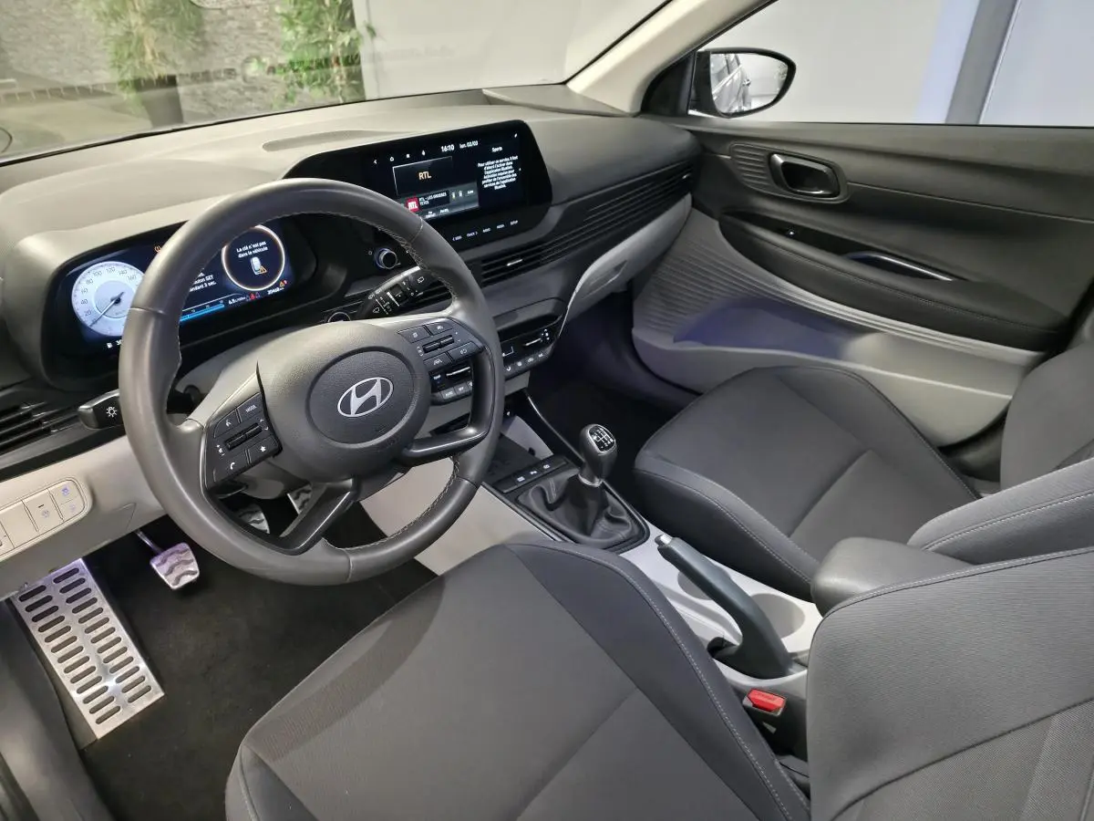 Vue intérieure côté conducteur du Hyundai Bayon 2025 gris, avec volant cuir, tableau de bord numérique et boîte manuelle.