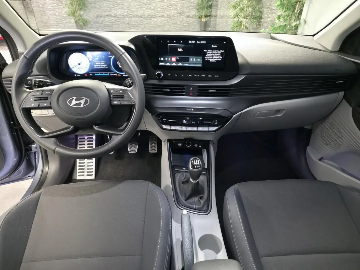 Vue intérieure avant du Hyundai Bayon 2025 essence gris, volant cuir, écran tactile 10,25 pouces et boîte manuelle.