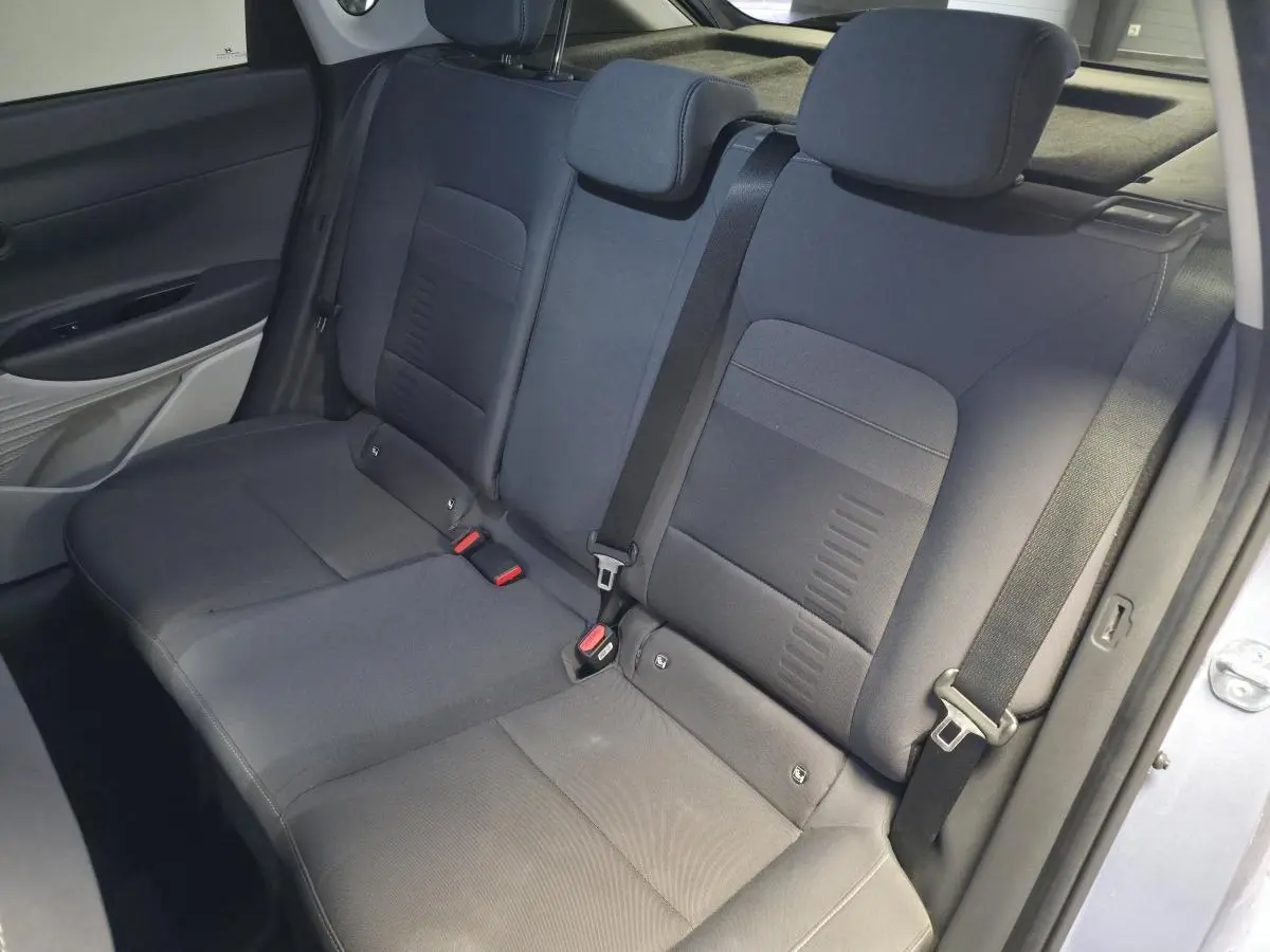 Vue intérieure côté arrière droit montrant la banquette arrière grise du Hyundai Bayon 2025 avec ceintures de sécurité visibles.