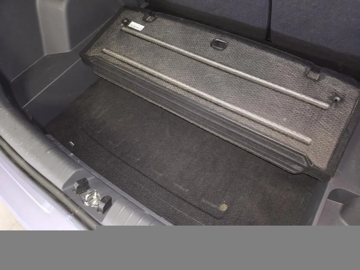 Vue rapprochée du coffre ouvert de la Hyundai Bayon gris, montrant le plancher modulable et la trappe de rangement.