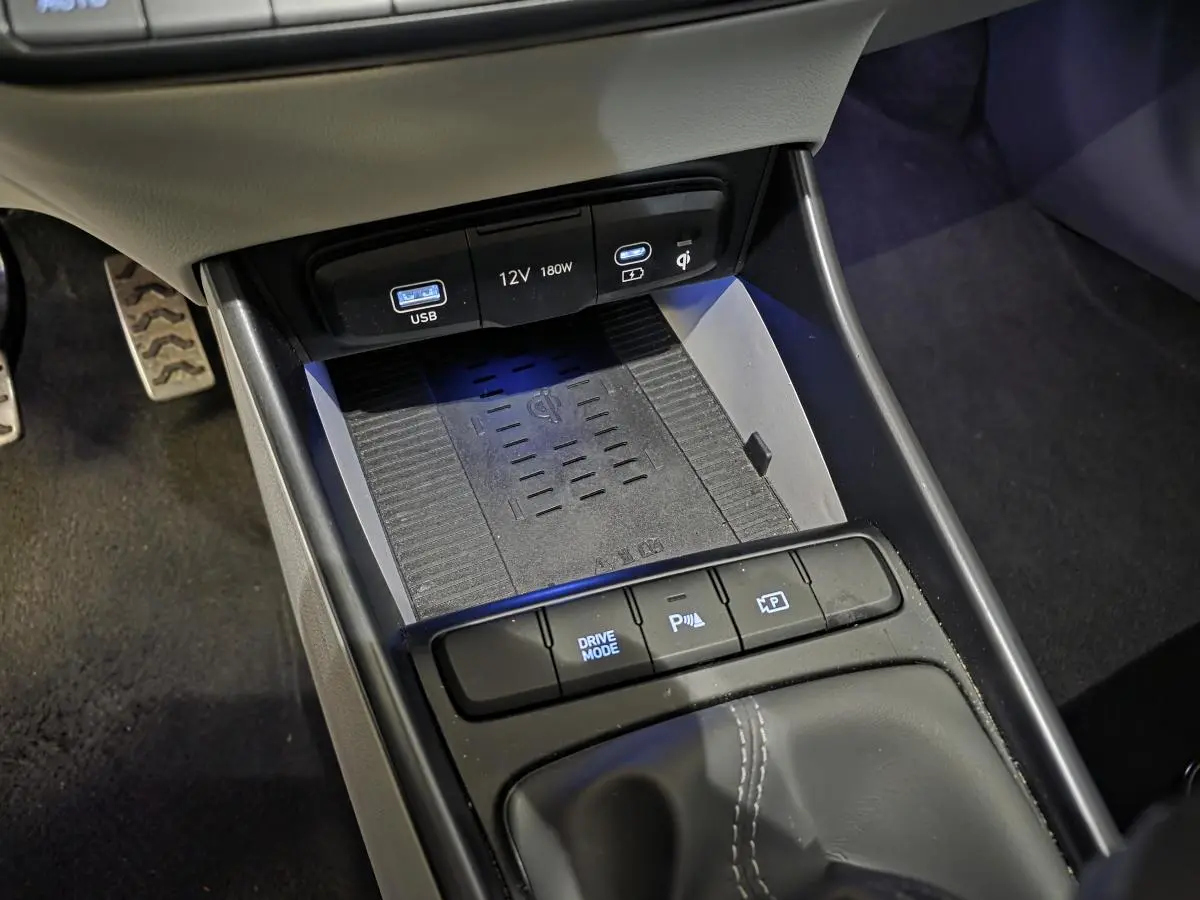 Gros plan sur la console centrale grise du Hyundai Bayon 2025 avec chargeur sans fil et ports USB éclairés.