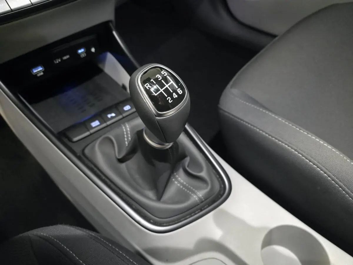 Gros plan sur le levier de vitesses manuel noir et gris clair du Hyundai Bayon 2025, intérieur tissu sombre.