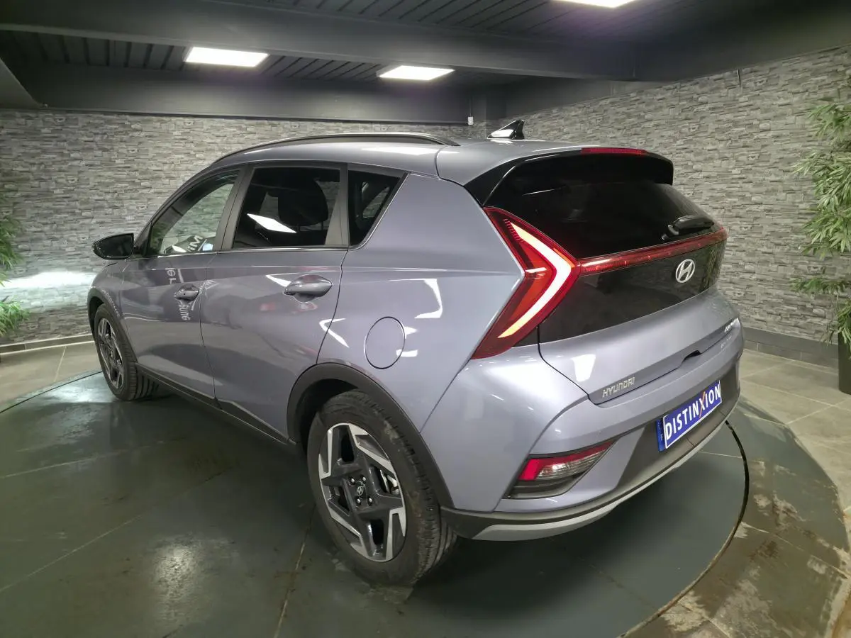 Vue 3/4 arrière droite du Hyundai Bayon gris métallisé avec feux arrière LED en forme de flèche et jantes alliage 17 pouces.