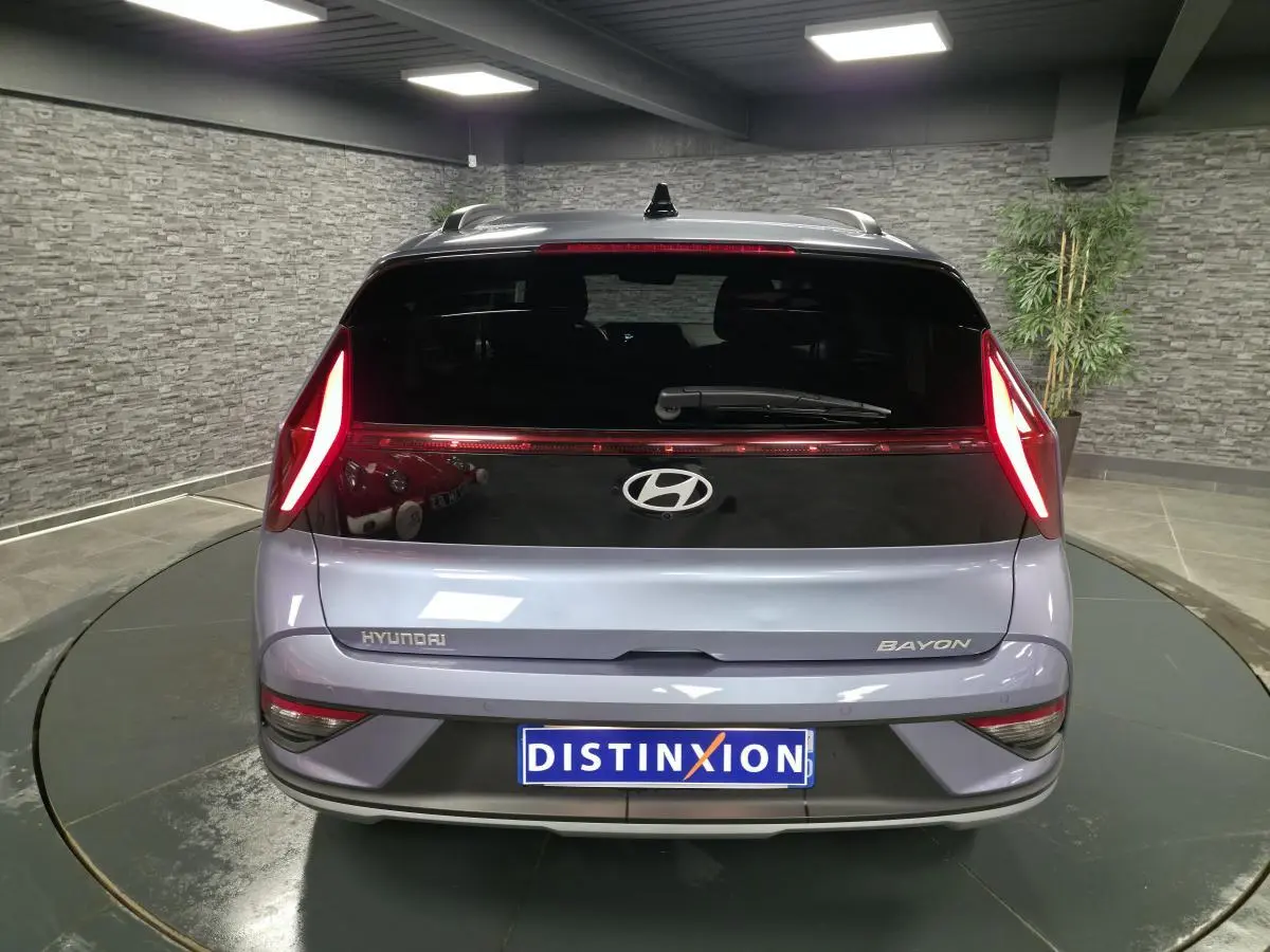 Vue arrière d'une Hyundai Bayon gris métallisé avec feux arrière LED en forme de boomerang et lunette noire brillante.