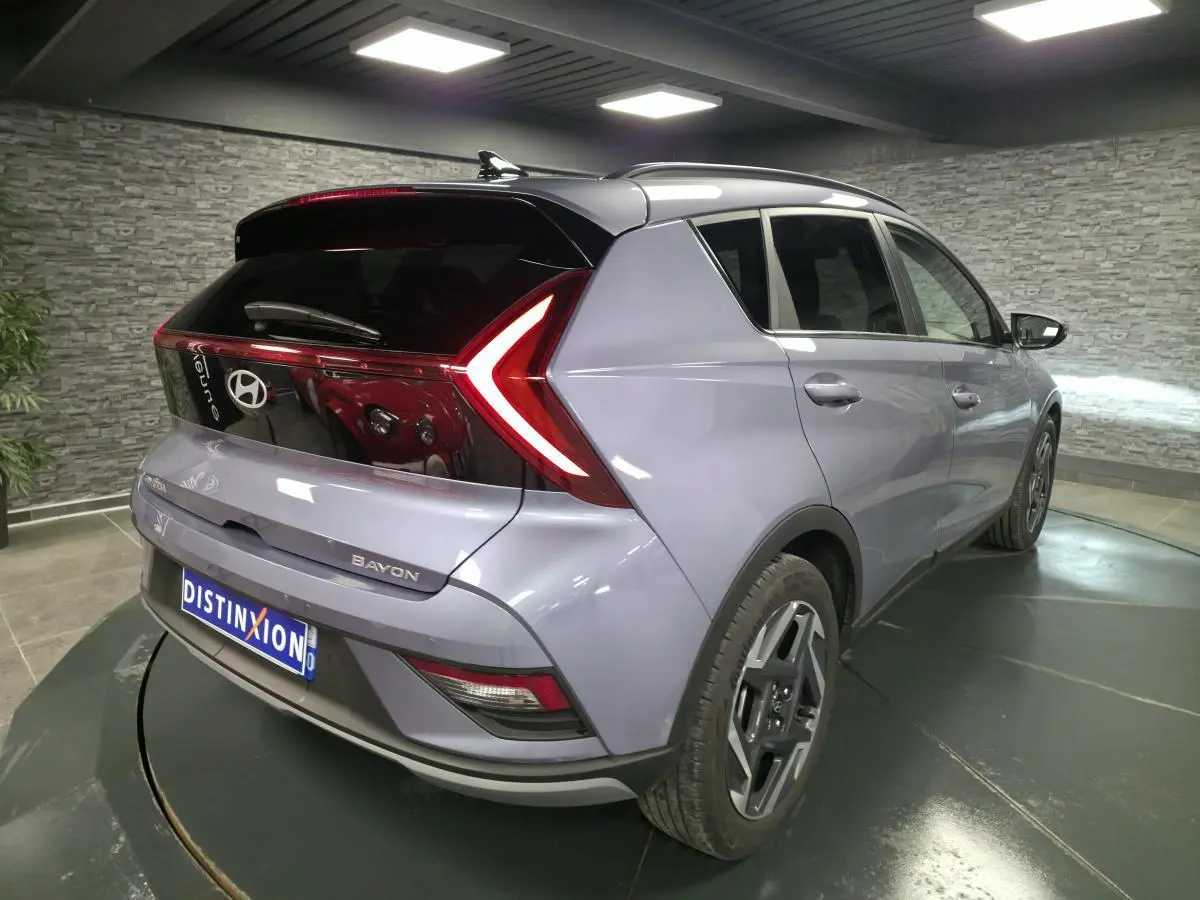 Vue 3/4 arrière droite d'une Hyundai Bayon gris métallisé avec feux arrière LED en forme de flèche et jantes alliage 17 pouces.