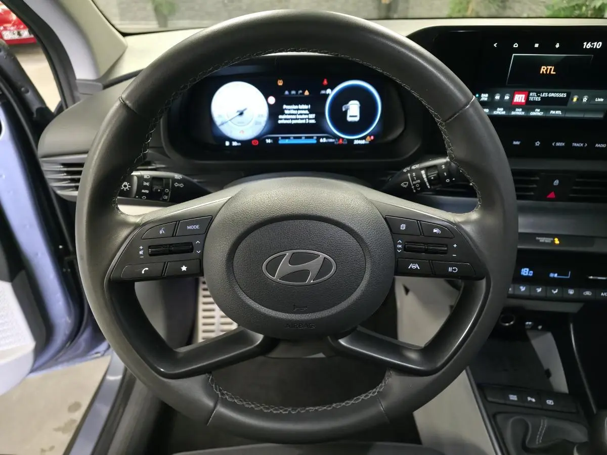 Vue intérieure centrée sur le volant cuir noir du Hyundai Bayon 2025 avec tableau de bord numérique et écran tactile.