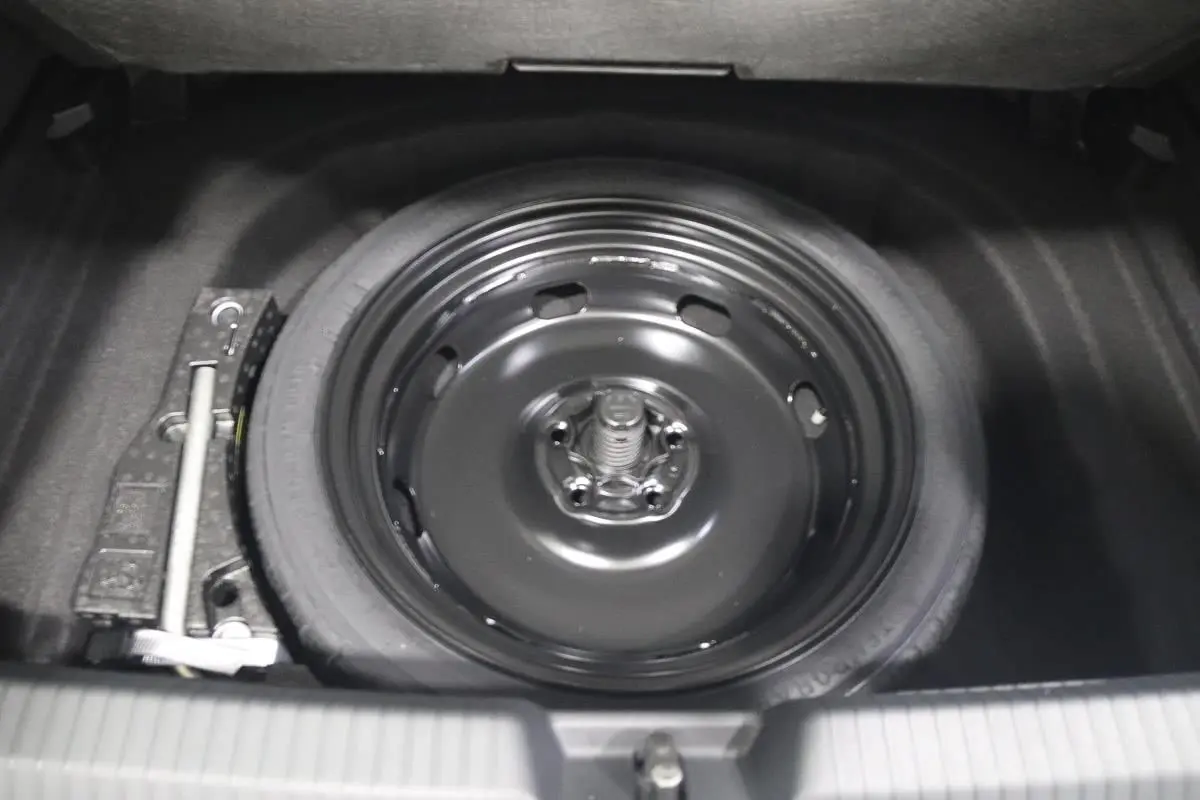 Gros plan sur la roue de secours noire dans le coffre d'une Volkswagen Golf 2.0 TDI 150 DSG R-Line blanche.