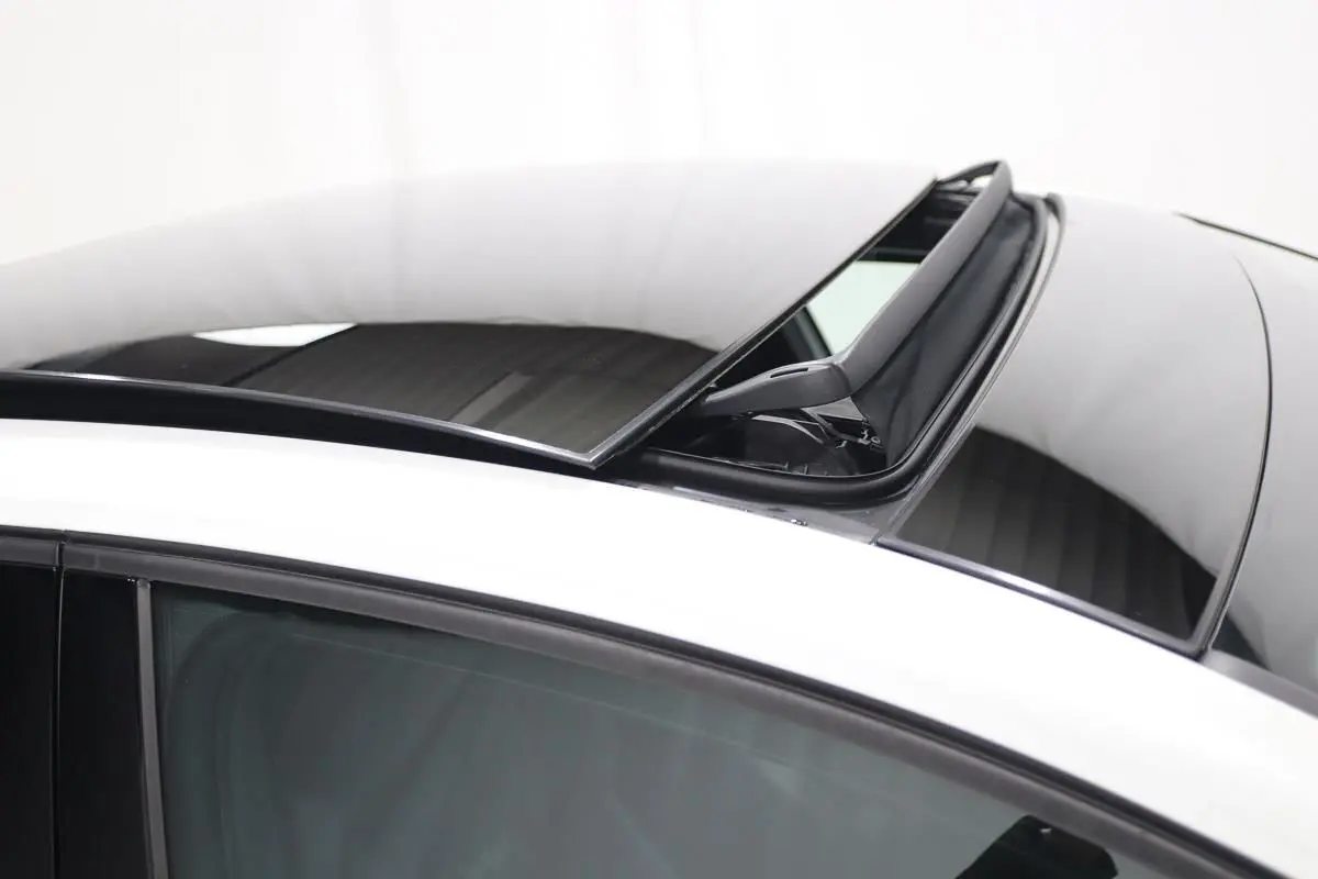 Toit panoramique ouvert sur une Volkswagen Golf blanche, vue rapprochée du toit et vitre côté gauche.