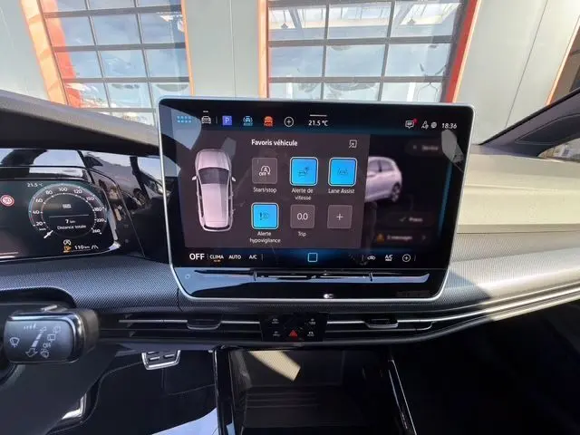 Vue intérieure du tableau de bord de la Volkswagen Golf 2025 blanche, avec écran tactile central affichant les aides à la conduite.