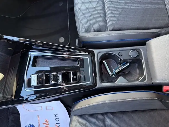 Vue plongeante sur la console centrale noire brillante et les sièges sport gris avec surpiqûres bleues d'une Volkswagen Golf 2.0 TDI 150 DSG R-Line.