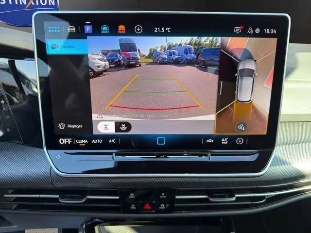 Écran central de la Volkswagen Golf 2025 blanc montrant la caméra 360° avec vue arrière et vue aérienne du véhicule.