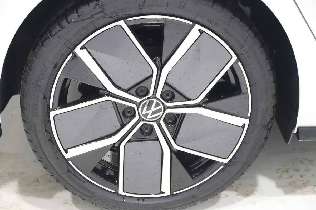 Gros plan sur la jante alliage noire et argentée de la Volkswagen Golf blanche, côté roue avant droite.