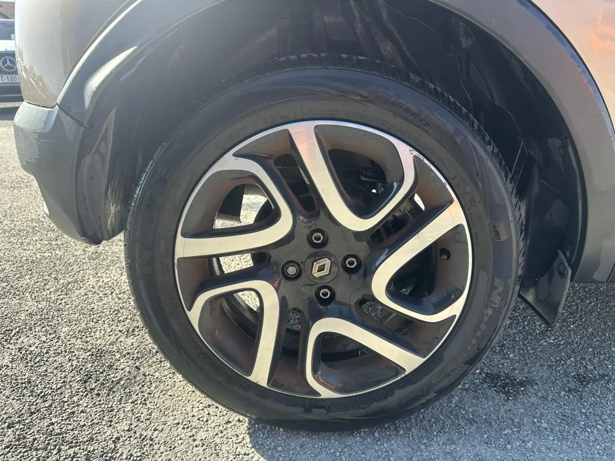 Gros plan sur la jante alliage 17 pouces noir diamanté du Renault Captur beige, avec logo Renault central.