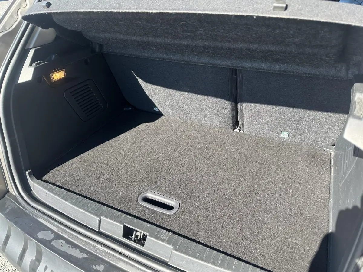 Coffre ouvert du Renault Captur beige 2014, vue arrière montrant un espace de chargement propre et tapis gris.