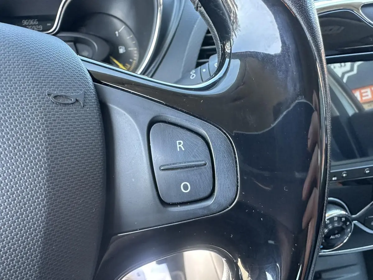 Gros plan sur le volant noir du Renault Captur 2014, avec boutons de commande et tableau de bord partiellement visible.