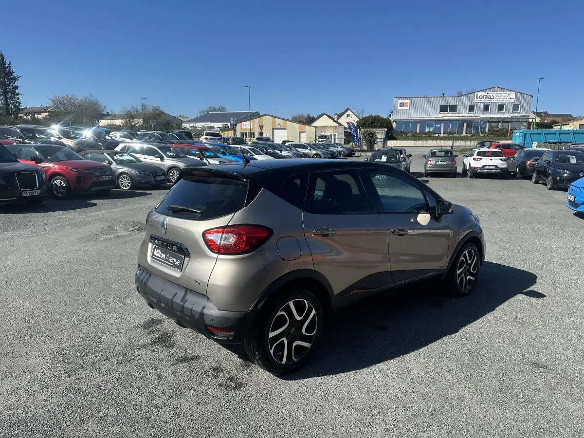 Renault Captur beige métallisé vue 3/4 arrière droit, toit noir et jantes alliage noires diamantées.