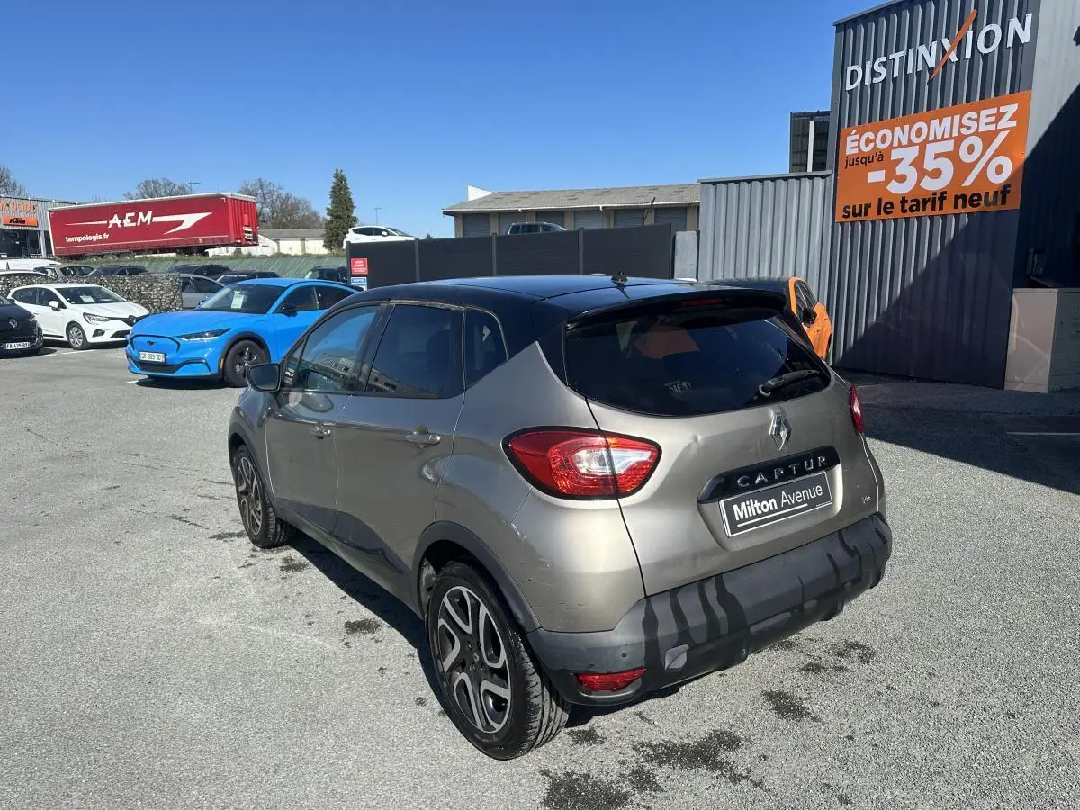 Vue 3/4 arrière droite d’un Renault Captur beige métallisé avec toit noir et jantes alliage noires diamantées.