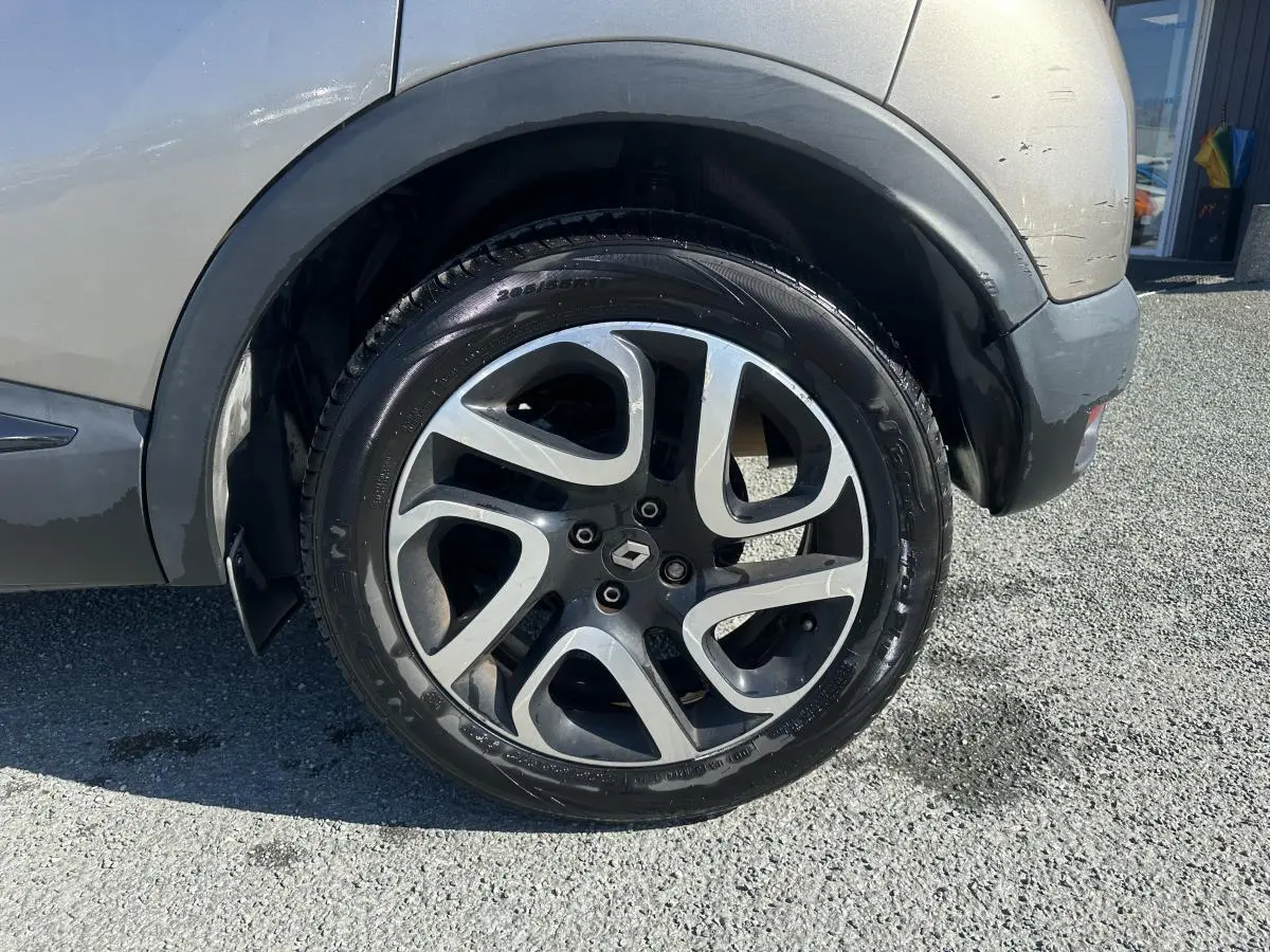 Gros plan sur la roue arrière droite du Renault Captur beige, jante alliage noir diamanté avec logo Renault central.