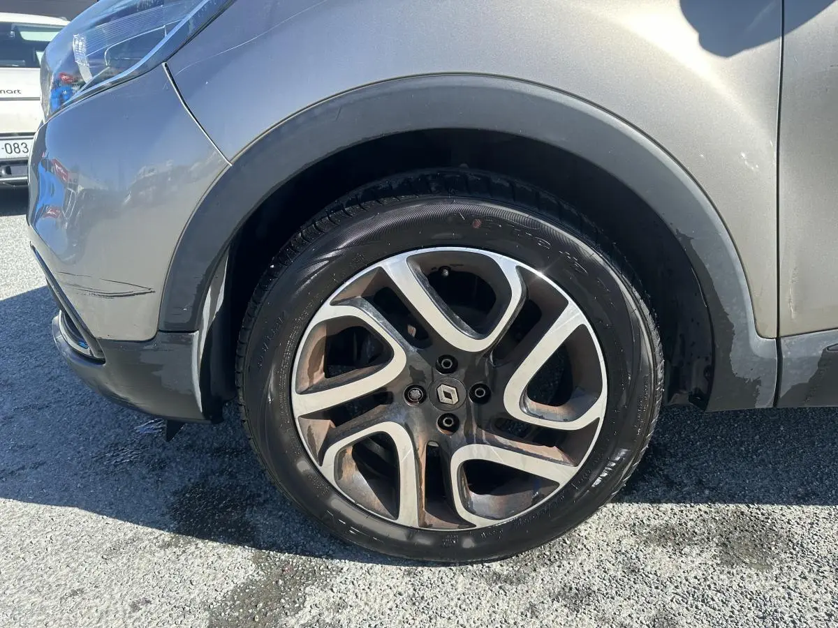 Gros plan sur la roue avant gauche alliage noir diamanté du Renault Captur beige 2014 avec jante stylisée.