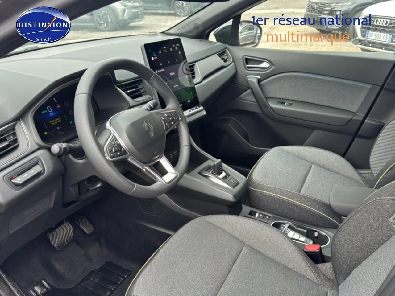 Vue intérieure côté conducteur du Renault Captur gris cassiopée, volant multifonction et écran tactile vertical au centre.