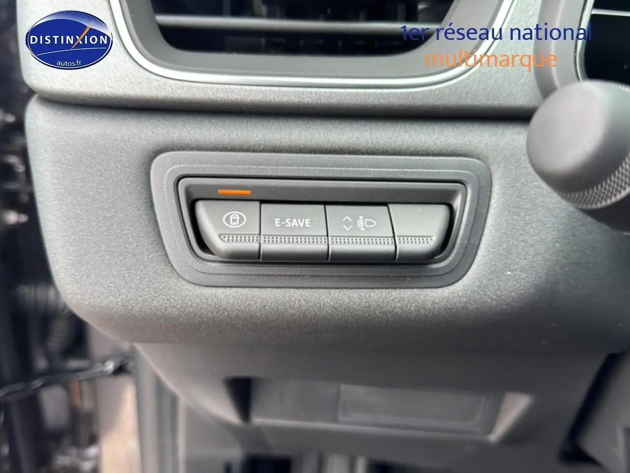 Gros plan sur les commandes E-SAVE et réglage des phares du tableau de bord gris du Renault Captur hybride 2026.