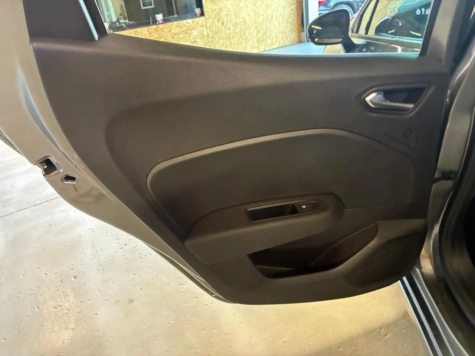 Vue rapprochée de la porte arrière gauche gris schiste de la Renault Clio 2025 avec poignée et commande de fenêtre intégrées.