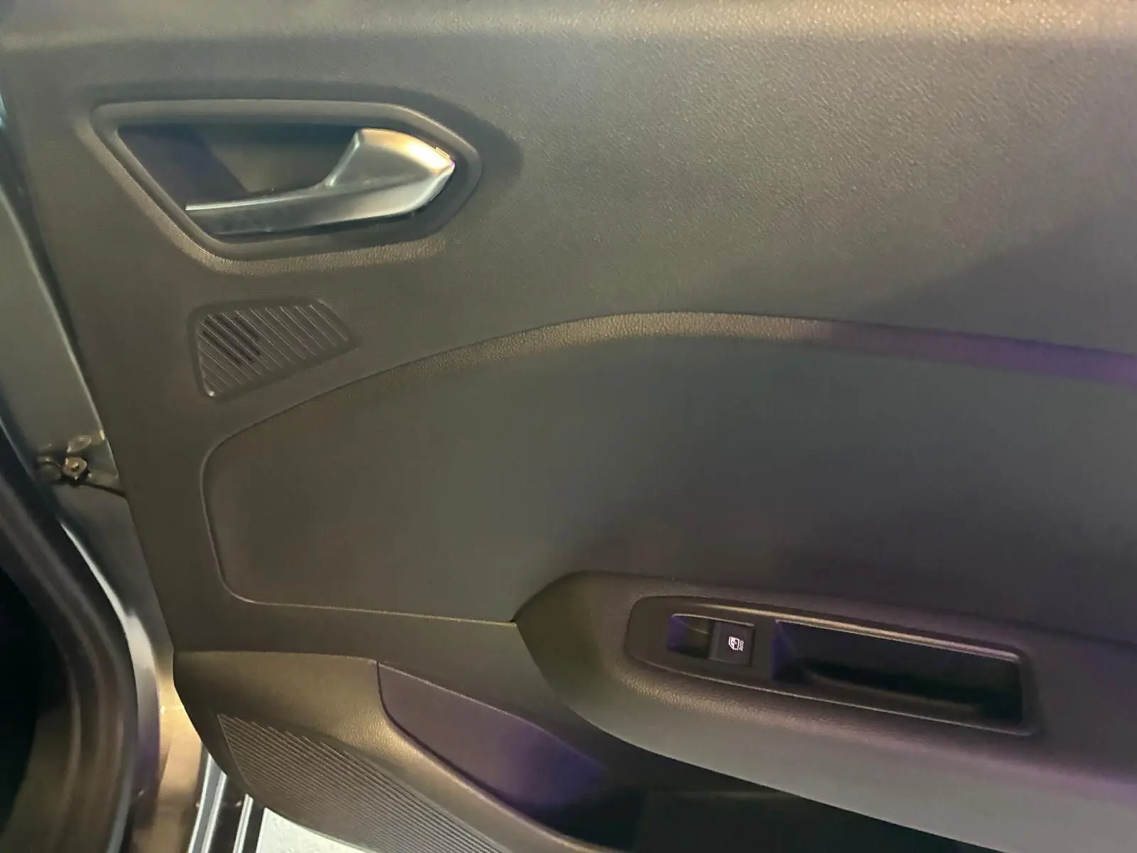 Détail de la porte intérieure côté gauche de la Renault Clio gris schiste, avec poignée argentée et commande de fenêtre.