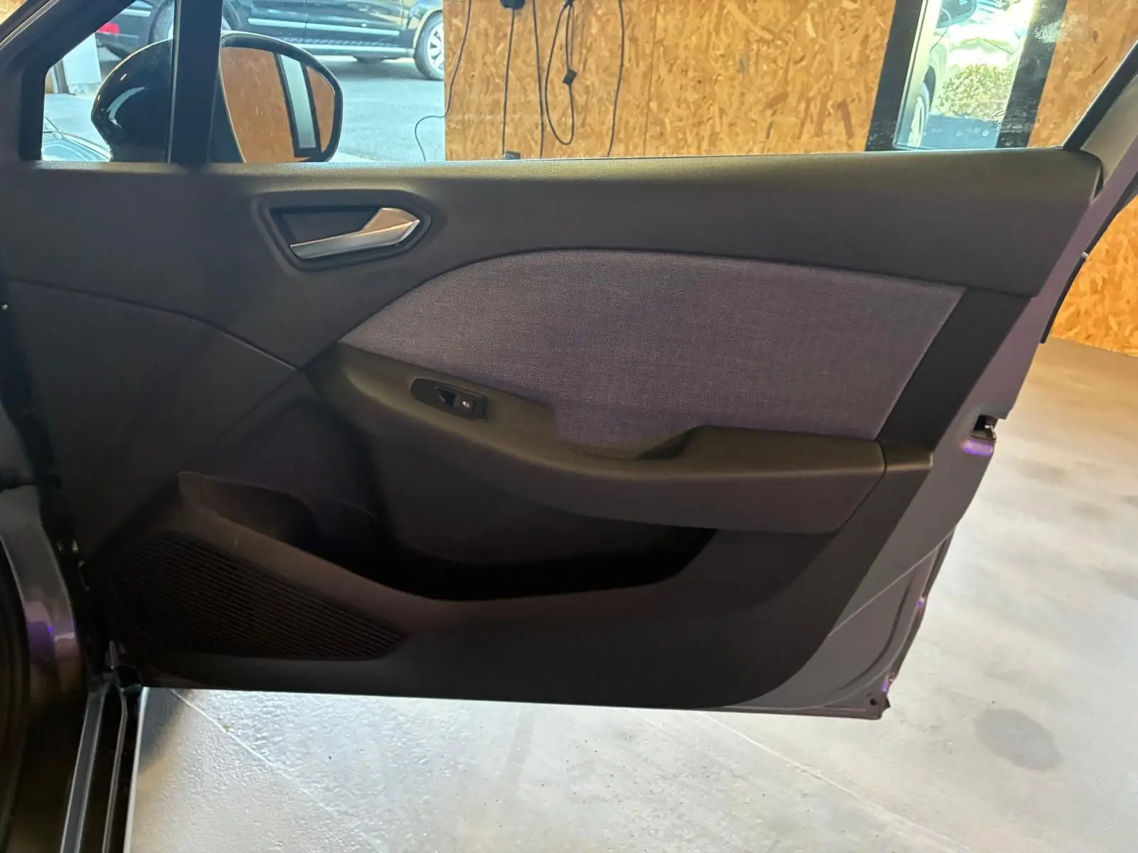 Vue intérieure de la porte avant gauche de la Renault Clio gris schiste, avec habillage tissu gris et commande de vitre.
