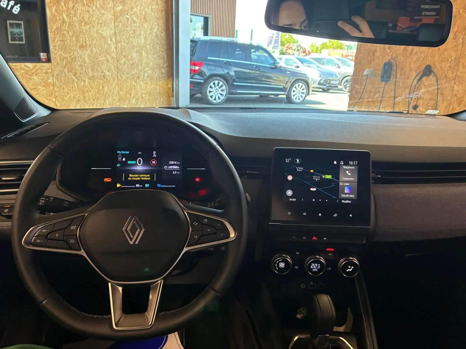 Vue intérieure centrée sur le volant et le tableau de bord numérique de la Renault Clio gris schiste avec écran tactile et commandes intégrées.