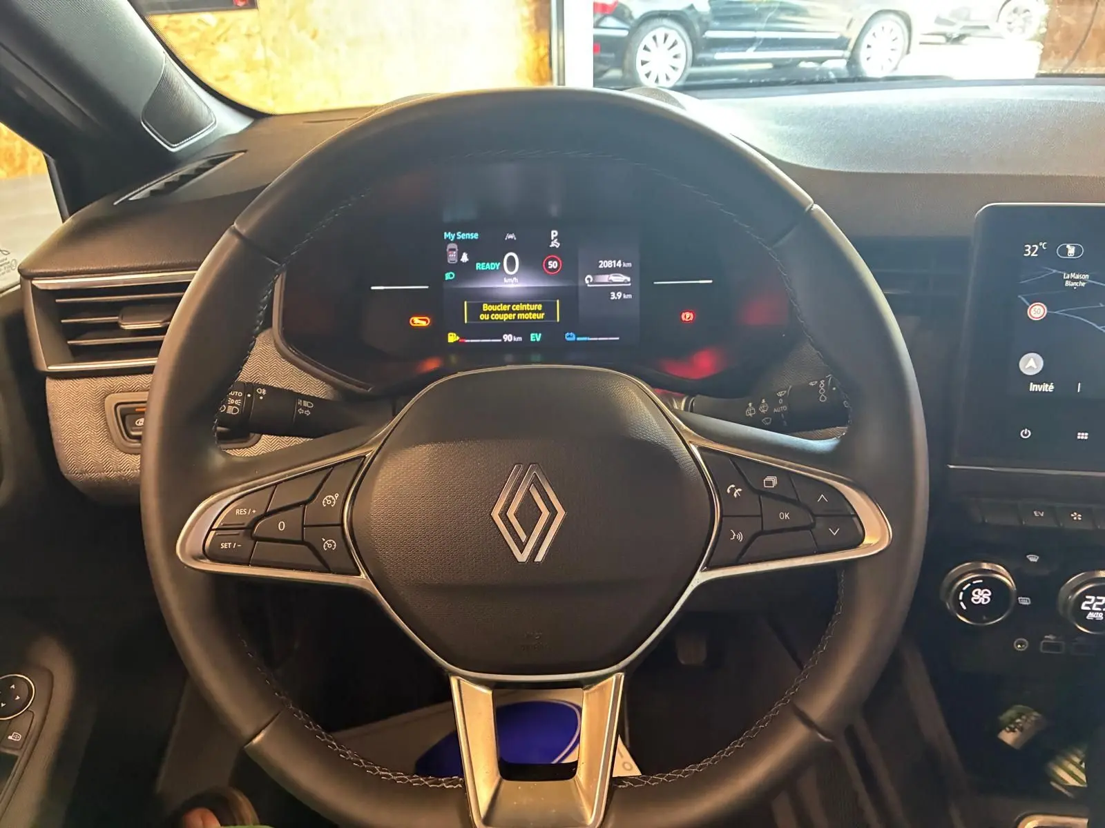 Vue intérieure centrée sur le volant noir de la Renault Clio 2025 avec tableau de bord numérique et écran tactile.