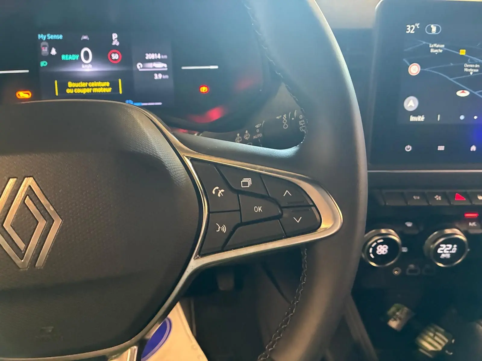 Gros plan sur le volant noir de la Renault Clio 2025 avec commandes intégrées et tableau de bord numérique lumineux.