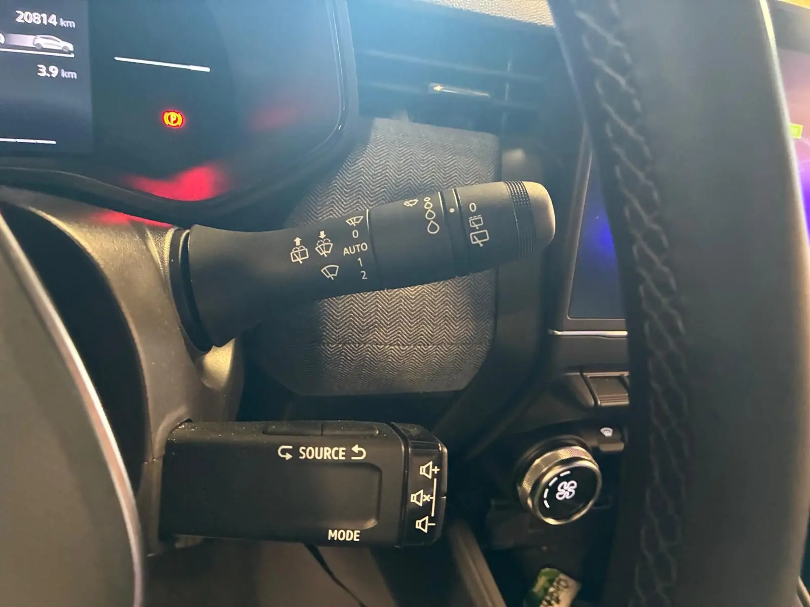 Gros plan sur la commande des essuie-glaces et du multimédia à gauche du volant d’une Renault Clio gris schiste, intérieur sombre.