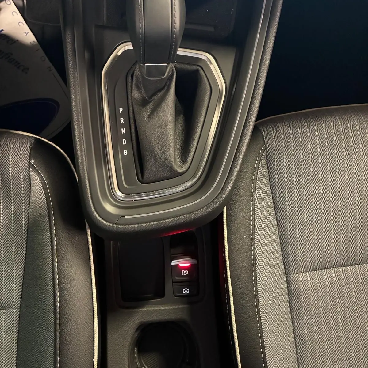 Vue plongeante sur la console centrale de la Renault Clio 2025, levier de vitesse automatique et siège tissu gris noir.