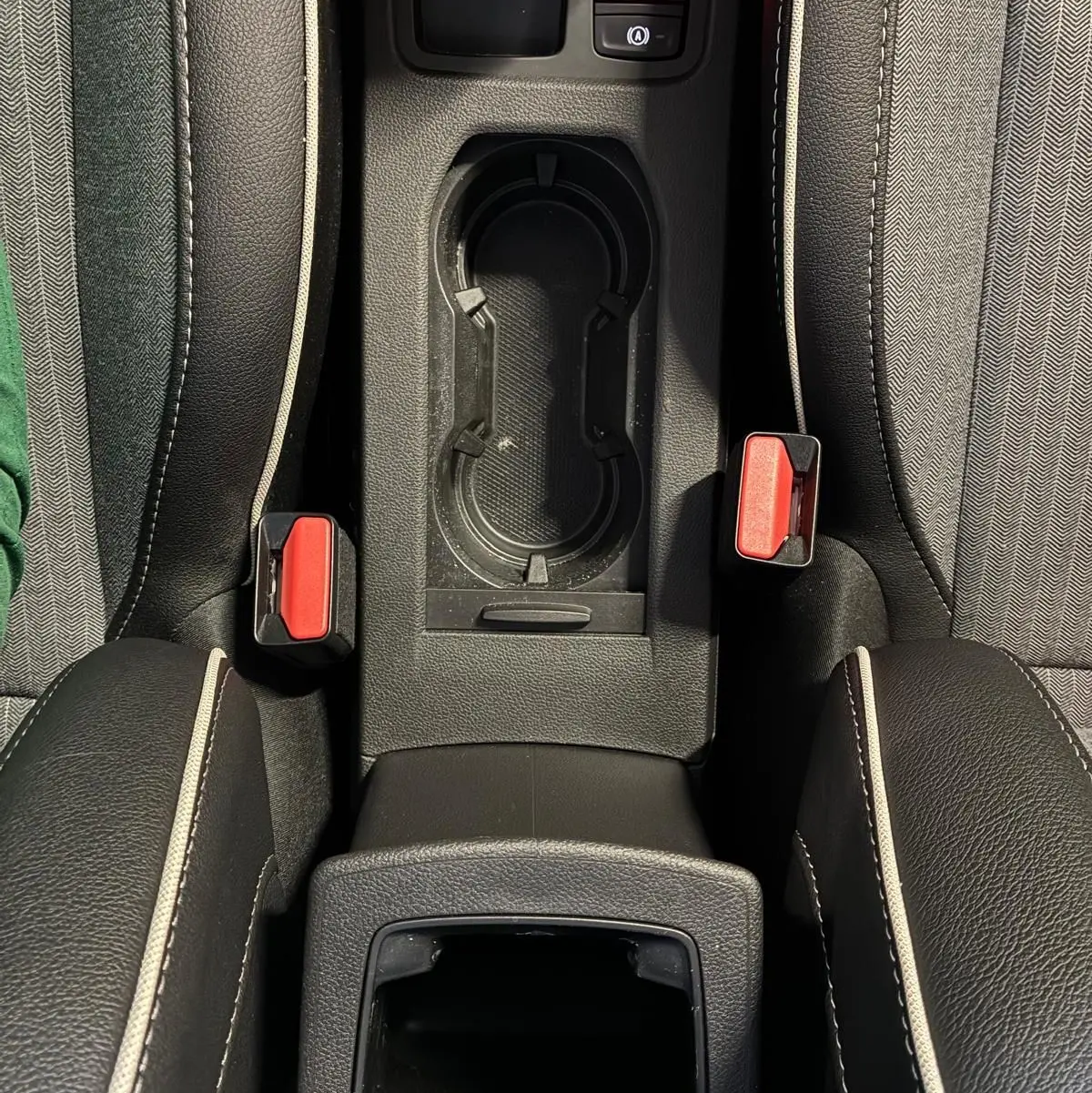 Vue plongeante sur la console centrale de la Renault Clio hybride 2025, avec porte-gobelets et boutons de frein à main électronique.