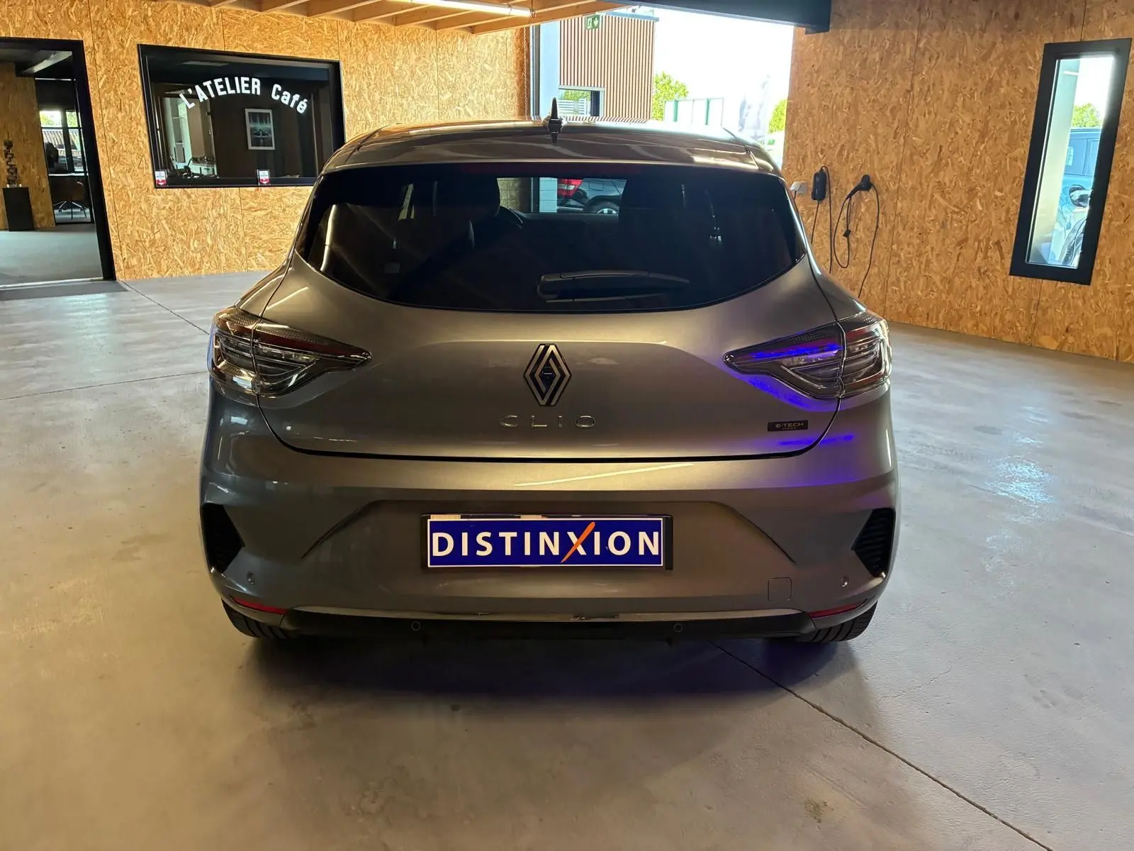 Vue arrière d'une Renault Clio gris schiste hybride 2025, avec feux LED et logo distinctif visible en intérieur.