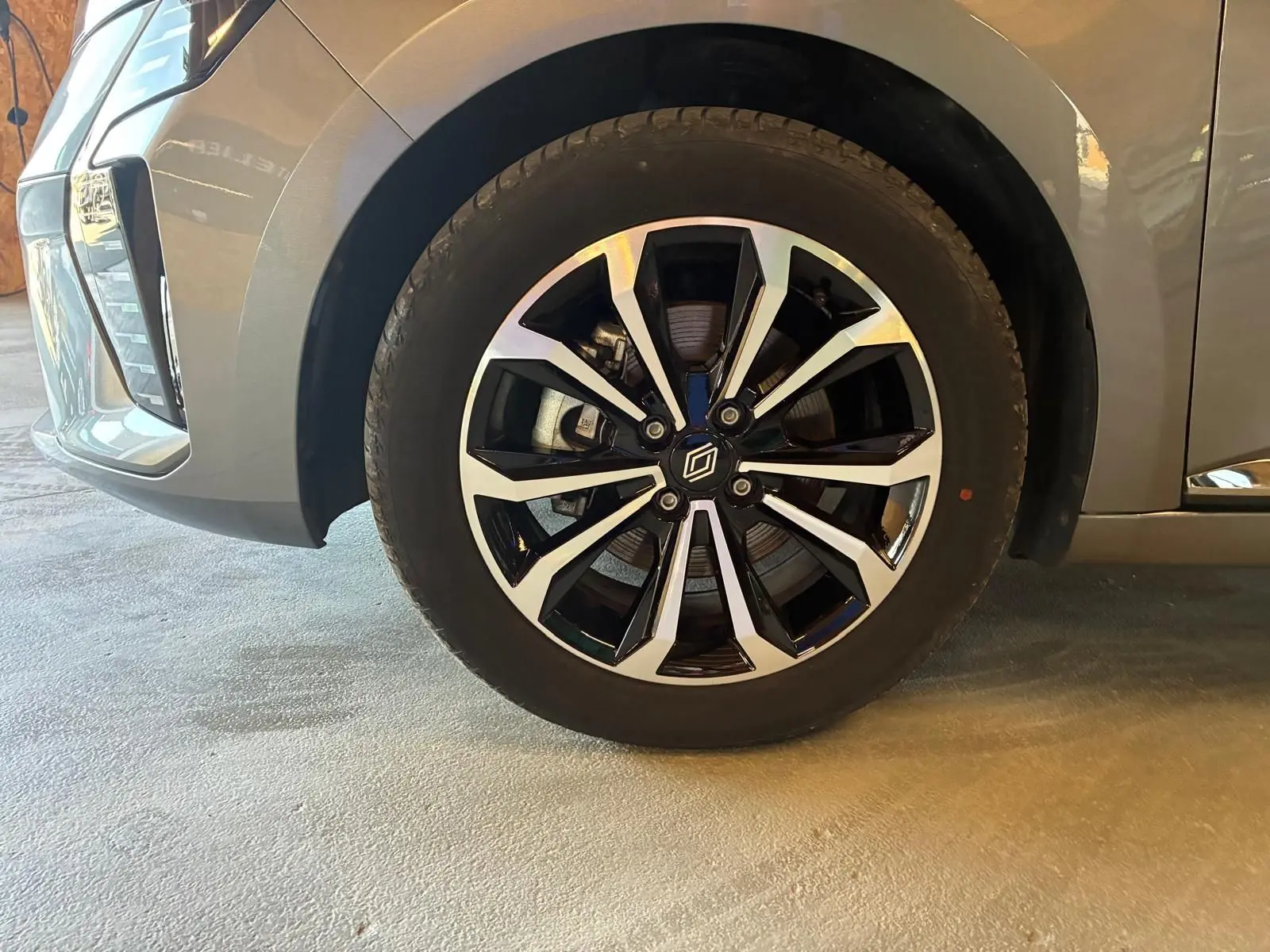Gros plan sur la roue avant gauche de la Renault Clio gris schiste, mettant en valeur la jante alliage bicolore au design moderne.