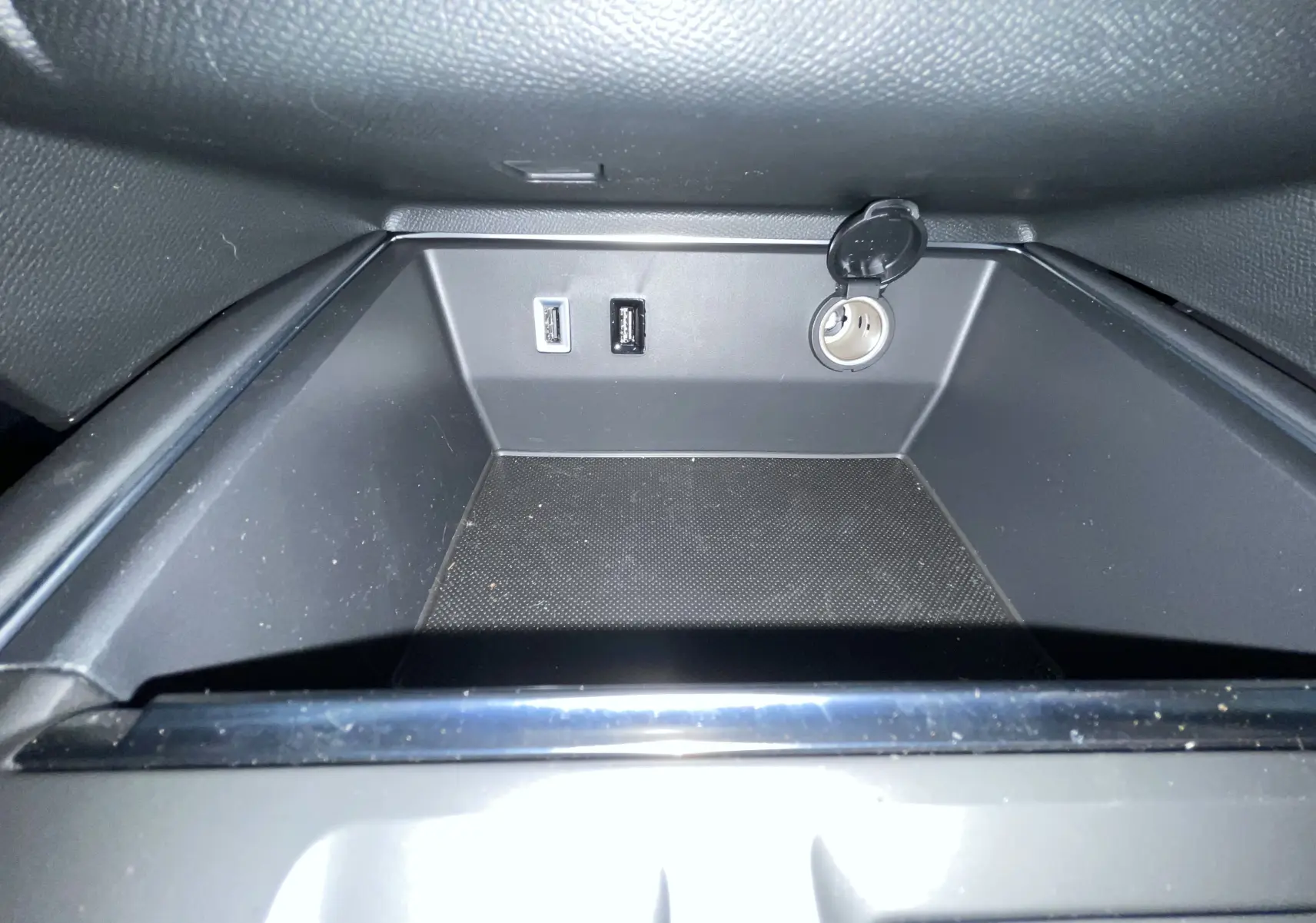 Gros plan de la prise 12V et ports USB dans le rangement central du Citroën C5 Aircross hybride blanc 2025.