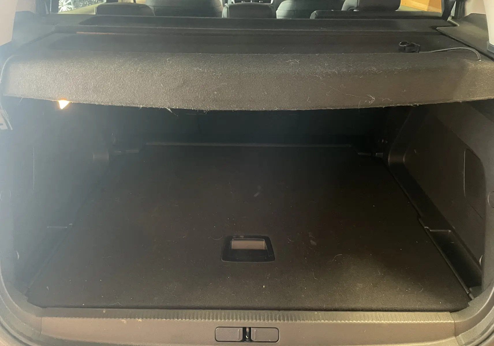 Coffre ouvert vu de l'arrière d'un Citroën C5 Aircross hybride blanc Okenite, espace de chargement vide avec cache-bagages.