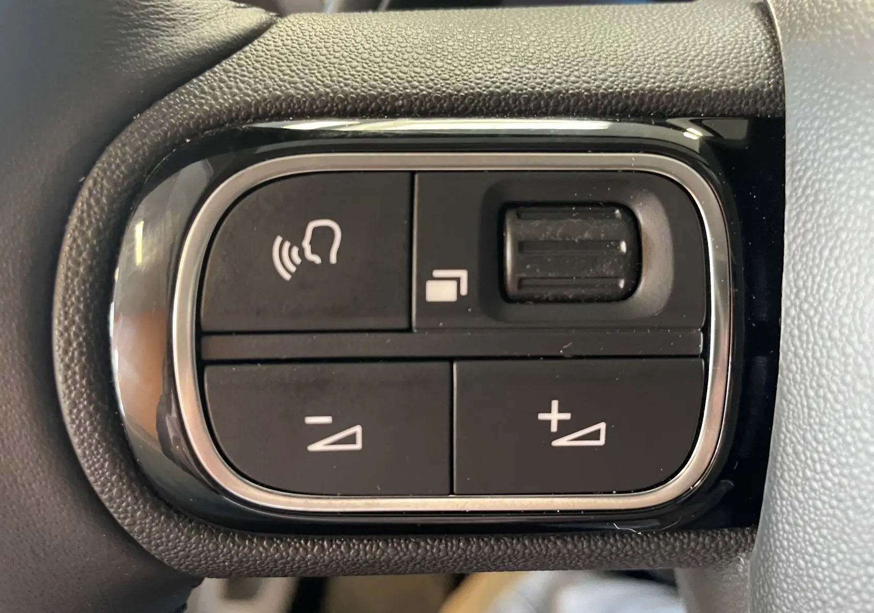 Gros plan sur les boutons de commande au volant du Citroën C5 Aircross blanc Okenite, version hybride 2025.