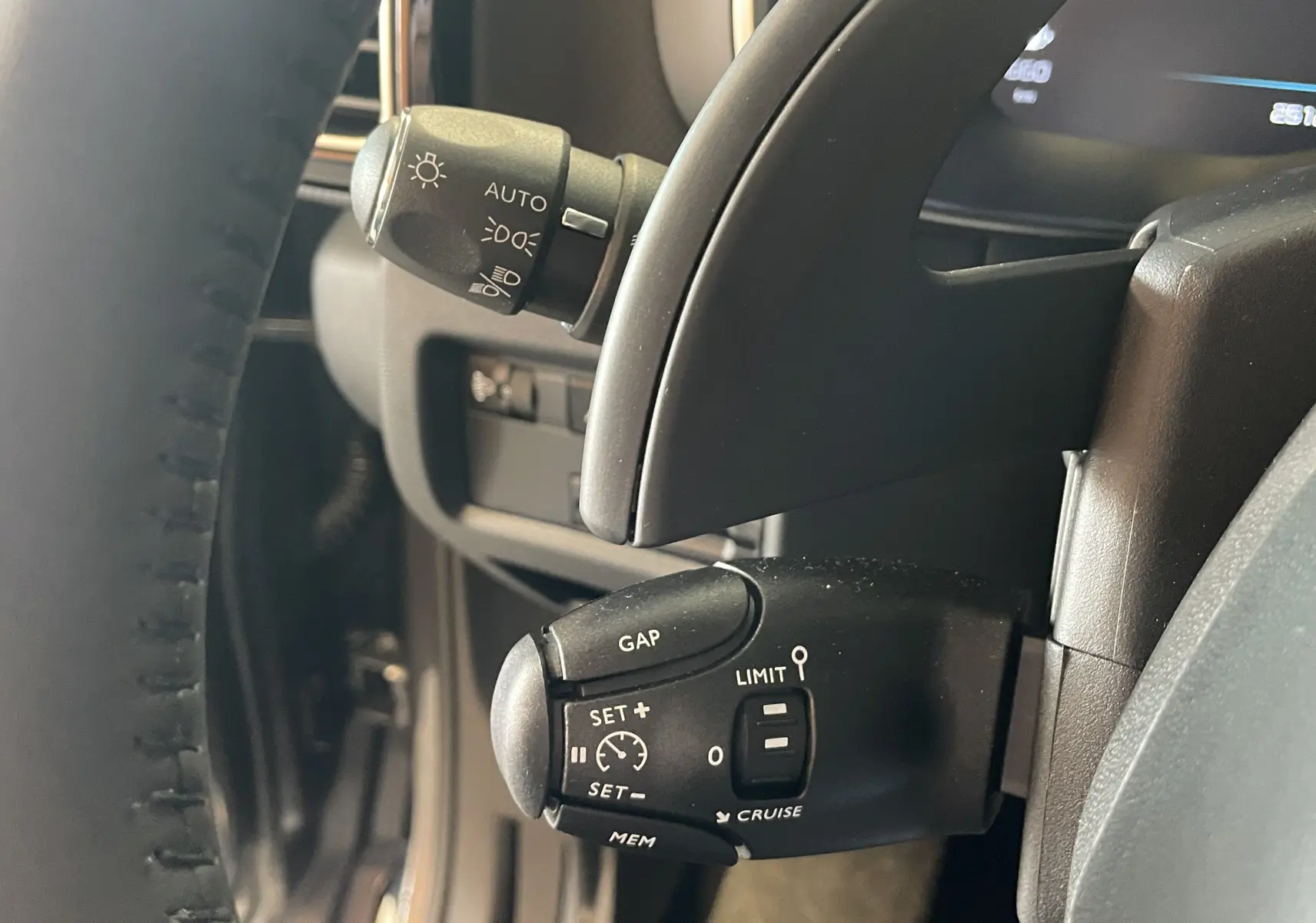 Gros plan sur la commande de régulateur de vitesse à gauche du volant d’un Citroën C5 Aircross hybride blanc 2025.