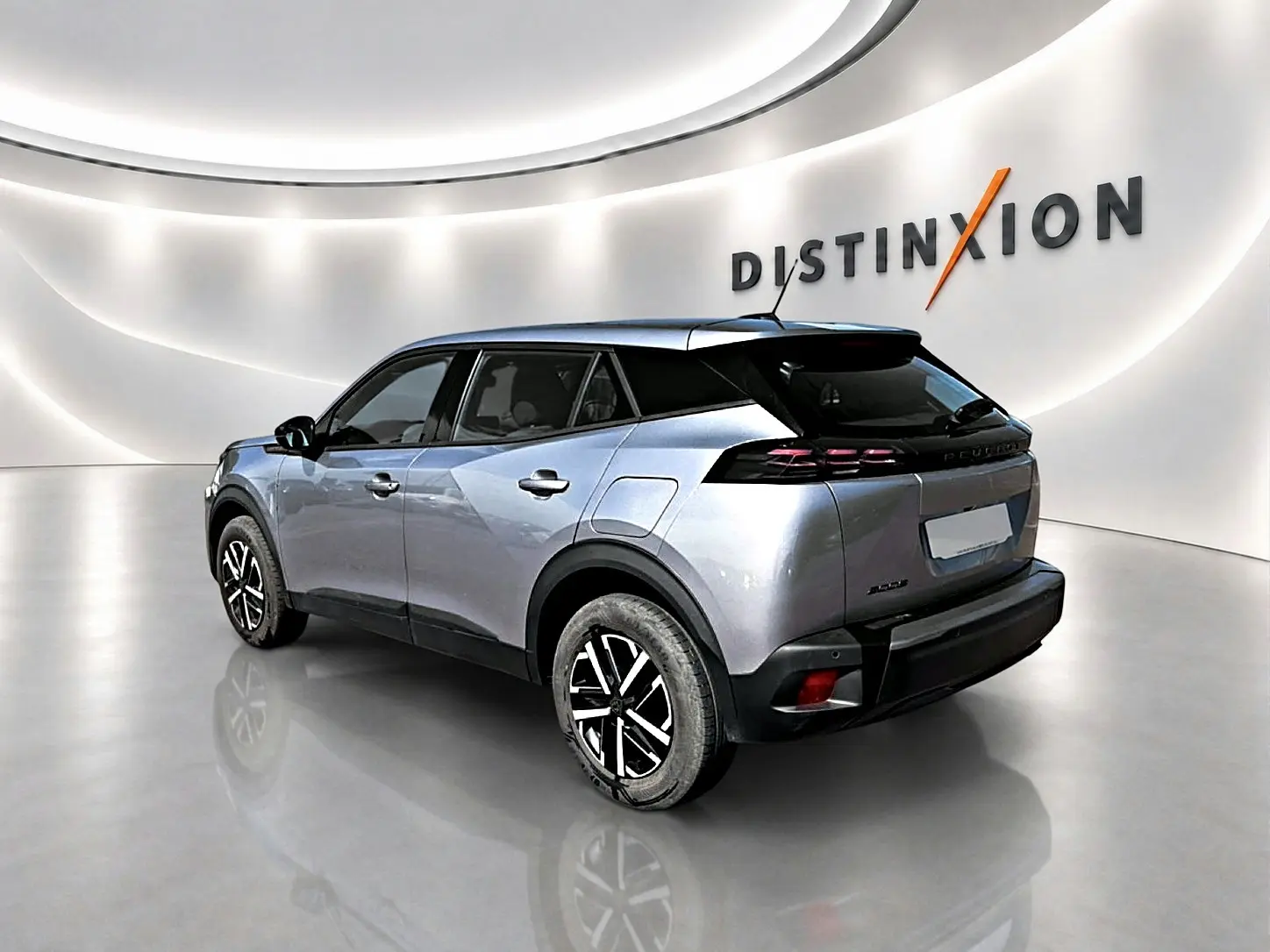 Peugeot 2008 gris 3/4 arrière droit en intérieur avec toit noir et jantes bicolores distinctives.